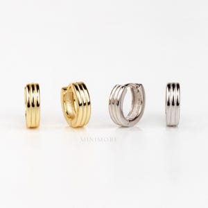 May include: Four small hoop earrings in gold and silver tones are displayed against a white background. The earrings have a ribbed design. The brand name "MINIMORE" is printed in the centre of the image.