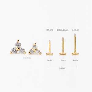 May include: Gold-toned labret studs with clear, round gemstones arranged in a triangular cluster. The image shows three different post lengths: 5mm, 6mm, and 8mm. The word "Labret" is written below the posts.