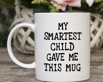 May include: White ceramic mug with black text that reads "My Smartest Child Gave Me This Mug".
