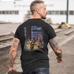 Pu&ograve; includere: Maglietta nera con una grafica di vigili del fuoco davanti a una bandiera americana. Il testo "We Will Never Forget" e "9-11-01" sono stampati sulla maglietta. La grafica include anche le parole "Bravery", "Sacrifice" e "Honor".
