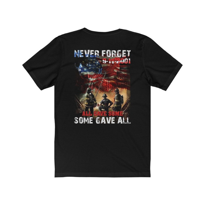 Pu&ograve; includere: Maglietta nera con una grafica di tre vigili del fuoco in piedi davanti a un edificio in fiamme con una bandiera americana che sventola al vento. Il testo "Never Forget 9-11-2001" &egrave; sopra la grafica e il testo "All Gave Some Some Gave All" &egrave; sotto la grafica.