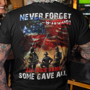 Pu&ograve; includere: Maglietta nera con una grafica della bandiera americana, vigili del fuoco e le Torri Gemelle. Il testo "Never Forget 9-11-2001" e "All Gave Some Some Gave All" &egrave; stampato sulla maglietta.