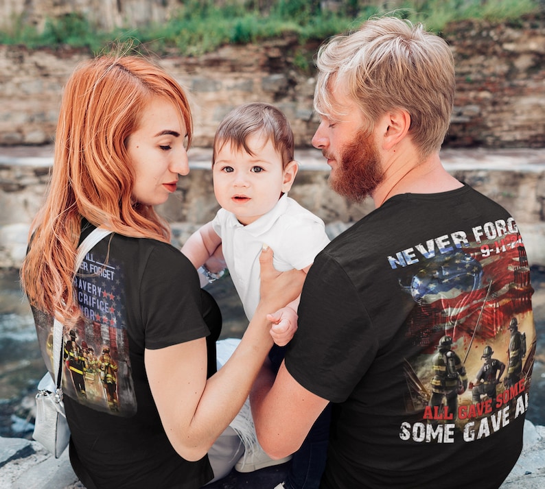 Pu&ograve; includere: Una famiglia indossa magliette nere con un'immagine di vigili del fuoco e il testo "Never Forget 9-11-01" e "All Gave Some, Some Gave All".