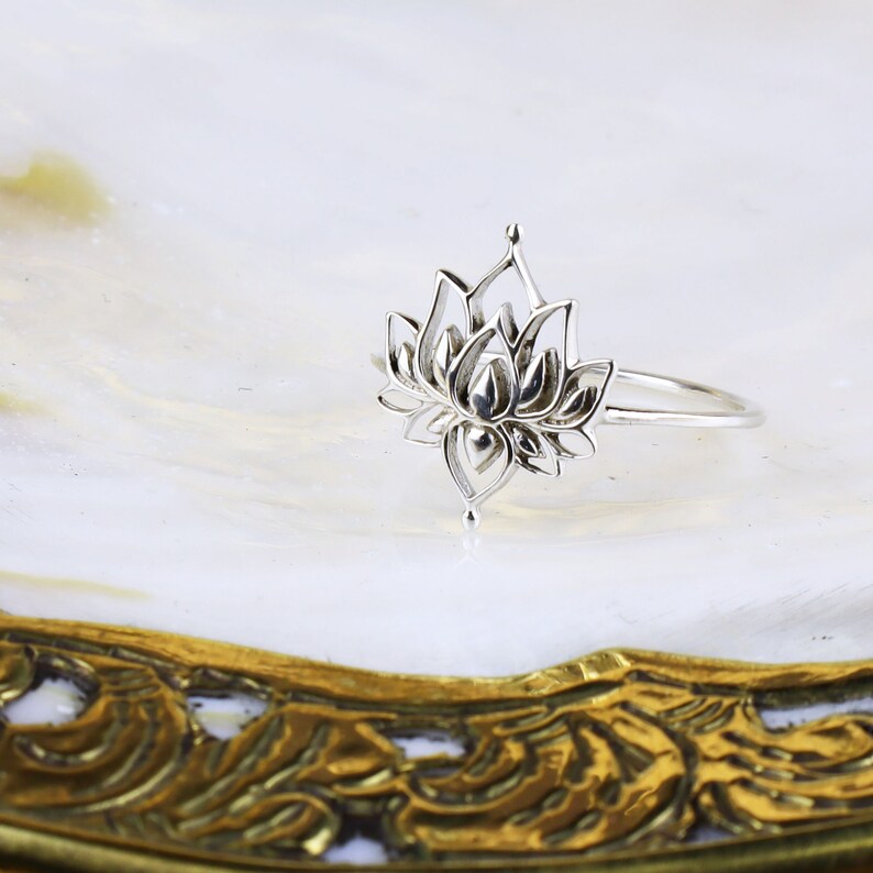 Puede incluir: Un anillo de plata con un delicado dise&ntilde;o de flor de loto. El anillo es abierto y ajustable.