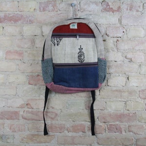 May include: A multi-colored hemp backpack with a zippered pocket and a small hemp leaf logo. The backpack has a blue, gray, red, and beige patchwork design.