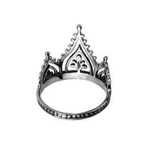 K&ouml;nnte beinhalten: Ein silberner Kronenring mit einem filigranen, komplizierten Design. Der Ring ist aus Metall und hat eine glatte, polierte Oberfl&auml;che.