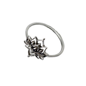 Puede incluir: Un anillo de plata con un dise&ntilde;o de flor de loto detallado.