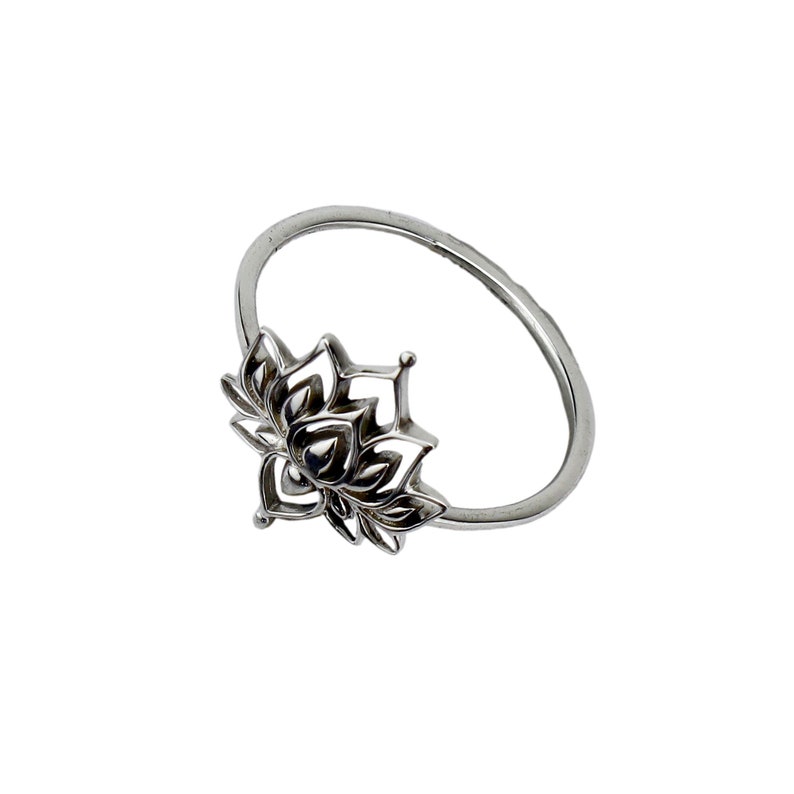 Puede incluir: Un anillo de plata con un dise&ntilde;o de flor de loto detallado.