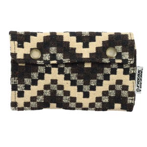 May include: A black and beige patterned fabric wallet with two metal buttons and the text "FREAK SCENE" on the right side.