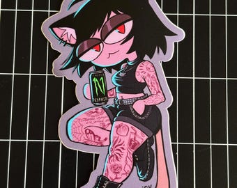 May include: A sticker featuring a cartoon cat-like character with black hair, red eyes, and tattoos. The character holds a green Monster energy drink can with the text "NYANSTE". The character wears a black outfit and boots.