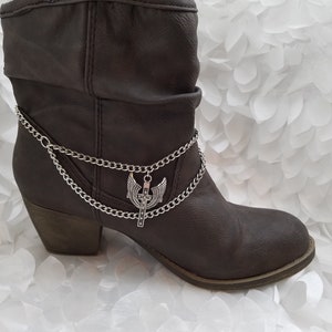 May include: Brown ankle boots with a silver chain and a silver charm with a cross and wings.