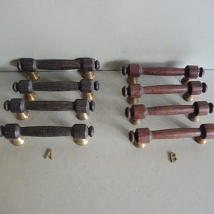 Peut inclure: Ensemble de poignées de meubles en bois avec des bases en laiton. Les poignées sont en deux groupes, l'un avec du bois brun foncé et l'autre avec du bois brun rougeâtre. Quincaillerie pour meubles.