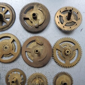 Pu&ograve; includere: Una collezione di ingranaggi in ottone di varie dimensioni e design. Gli ingranaggi, con la loro tonalit&agrave; dorata, presentano denti intricati, suggerendo che siano componenti di un dispositivo meccanico. Alcuni hanno alberi centrali o elementi di montaggio.
