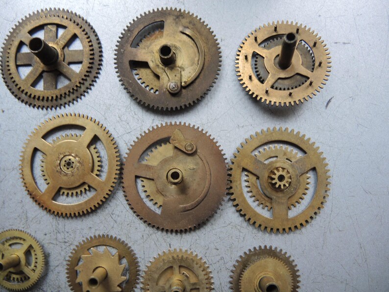Pu&ograve; includere: Una collezione di ingranaggi in ottone di varie dimensioni e design. Gli ingranaggi, con la loro tonalit&agrave; dorata, presentano denti intricati, suggerendo che siano componenti di un dispositivo meccanico. Alcuni hanno alberi centrali o elementi di montaggio.