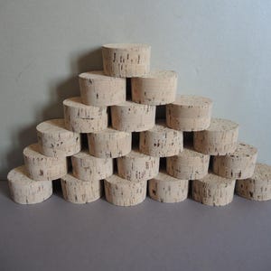 Peut inclure: Une pyramide de bouchons cylindriques en liège clair, chacun avec une surface texturée. Les bouchons sont empilés avec soin, mettant en valeur leur grain naturel et leur forme. Idéal pour les produits liés au vin ou l'artisanat.