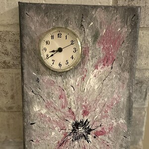 May include: Abstract painting on canvas with a clock face in the upper left corner. The painting features a gray, white, and pink color scheme with black accents. The clock face is white with black numbers and hands.