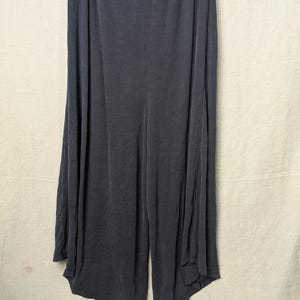 May include: Dark gray wide-leg pants made of a soft, ribbed fabric. The pants have a high waist and a flowing, relaxed fit. The fabric drapes elegantly, creating a comfortable and stylish look.