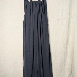 May include: A dark gray maxi dress with spaghetti straps, hanging on a wooden hanger. The dress has a gathered neckline and a flowing, floor-length design. The fabric appears soft and drapes gracefully.