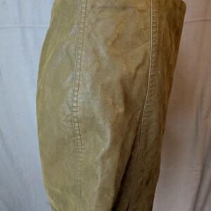 May include: Olive green leather skirt with vertical seam detailing. The skirt has a fitted silhouette and appears to be made of a soft, supple leather. The seams are stitched with a matching thread, adding to the skirt's tailored look.