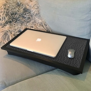 May include: A black laptop tray with a grey laptop and a grey computer mouse on a grey sofa.