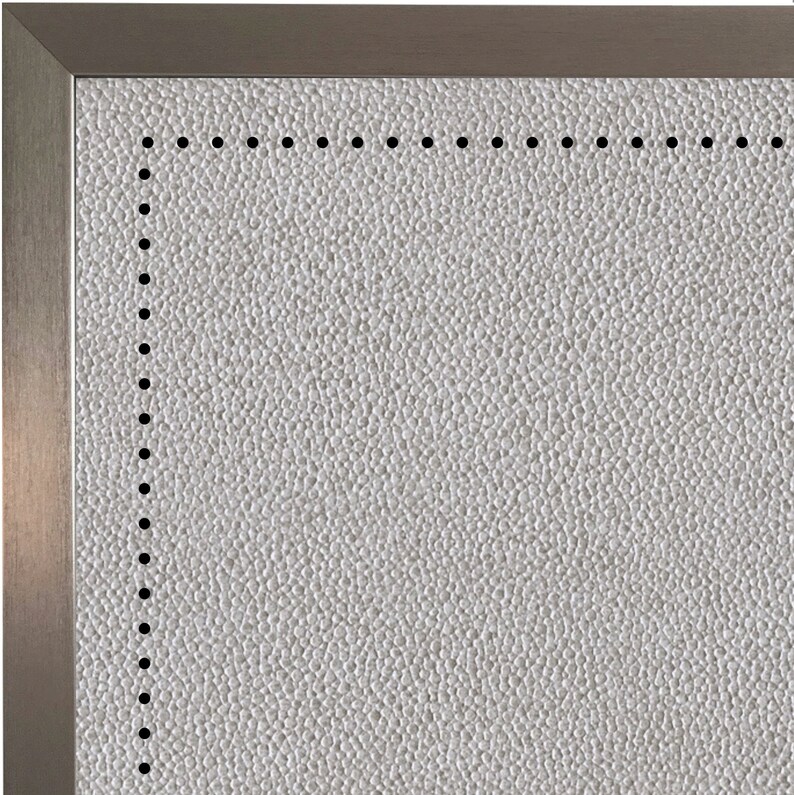 May include: Close-up of a white textured surface with a silver frame. The surface has a dotted border.