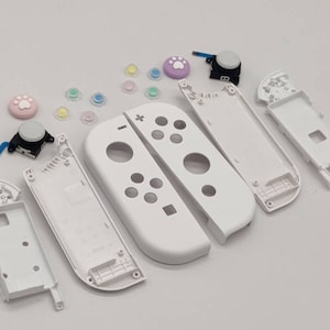 May include: White replacement parts for a Nintendo Switch controller. The parts include the faceplate, backplate, and buttons.
