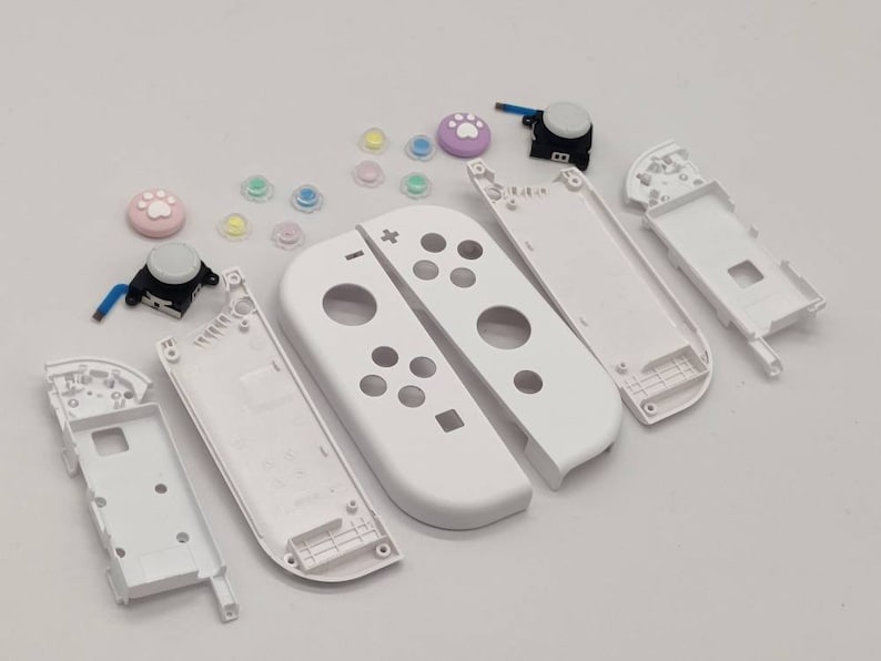 Puede incluir: Piezas de repuesto blancas para un mando de Nintendo Switch. Las piezas incluyen la placa frontal, la placa posterior y los botones.