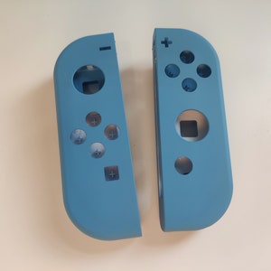 Könnte beinhalten: Zwei hellblaue Joy-Con-Controller für die Nintendo Switch, getrennt und mit der Anordnung der Tasten.