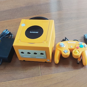 May include: A yellow Nintendo GameCube console with a matching yellow controller, power adapter, and AV cable. The console has a black disc drive slot and four memory card slots.