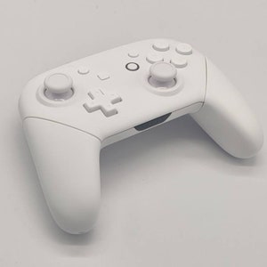 May include: A white wireless video game controller with a directional pad, four face buttons, two analog sticks, and two shoulder buttons.