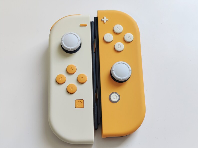 Puede incluir: Un mando Nintendo Switch Joy-Con blanco y amarillo con botones y joysticks blancos.