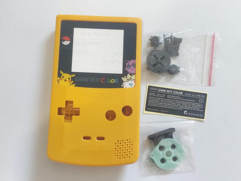 K&ouml;nnte beinhalten: Gelbe Game Boy Color Konsole mit schwarzem Bildschirm und verschiedenen Ersatzteilen. Die Konsole zeigt Pikachu und andere Pok&eacute;mon-Charaktere. Enth&auml;lt einen Aufkleber mit dem Text "GAME BOY COLOR".
