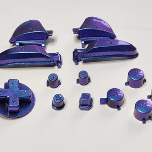 May include: A set of purple and blue video game controller buttons and faceplates. The faceplates have the letters L and R on them. The buttons have the letters A, B, X, Y, and directional arrows.