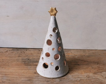 May include: White ceramic Christmas tree with a gold star on top. The tree is decorated with small holes and a speckled glaze.