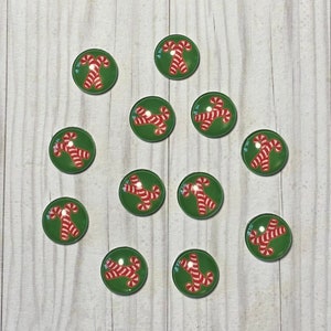 May include: Twelve round green and white candy cane Christmas ornaments. Each ornament features a red and white candy cane on a green background.