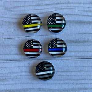 May include: Five round glass cabochons with an American flag design. Each cabochon has a thin colored stripe across the flag, in yellow, green, red, blue, and gray.
