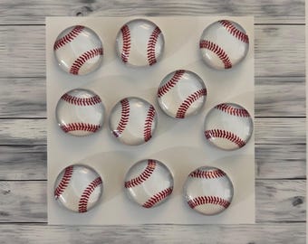 May include: Ten round glass cabochons with a baseball design. The cabochons are white with red stitching and are arranged in a grid pattern on a white background.