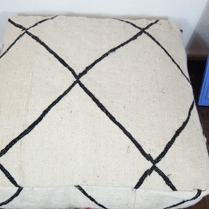 Puede incluir: Un coj&iacute;n de suelo blanco con patrones de diamantes negros. El coj&iacute;n est&aacute; hecho de una tela suave y tejida.