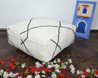 Op de afbeelding: Een wit vloer kussen met zwarte geometrische ontwerpen. Het kussen is gemaakt van een zacht, pluche materiaal en is perfect om een ​​bohemien stijl aan elke kamer toe te voegen.