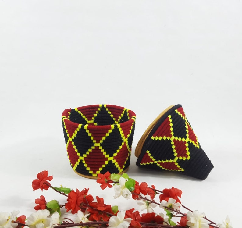 K&ouml;nnte beinhalten: Zwei geflochtene K&ouml;rbe mit einem geometrischen Muster in Rot, Schwarz und Gelb. Die K&ouml;rbe sind aus einem weichen, biegsamen Material gefertigt und haben ein einzigartiges, handgefertigtes Aussehen.
