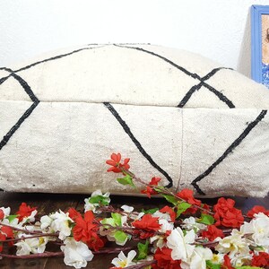 Puede incluir: Un coj&iacute;n de suelo blanco y negro con un dise&ntilde;o de diamante. El coj&iacute;n est&aacute; hecho de un tejido suave y tejido y es perfecto para agregar un toque de estilo bohemio a cualquier habitaci&oacute;n.