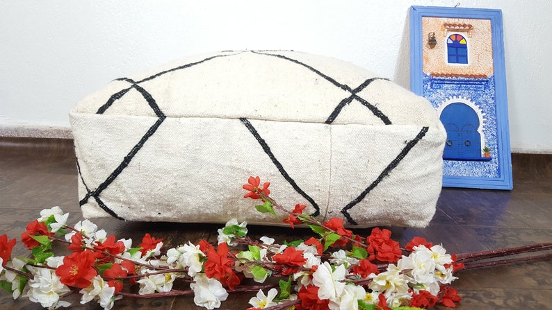 Puede incluir: Un coj&iacute;n de suelo blanco y negro con un dise&ntilde;o de diamante. El coj&iacute;n est&aacute; hecho de un tejido suave y tejido y es perfecto para agregar un toque de estilo bohemio a cualquier habitaci&oacute;n.