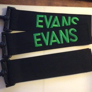 May include: Three black fabric wristbands with green embroidered text. The text reads "Evanc Evans".