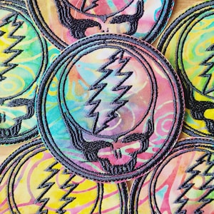 May include: A set of six colorful embroidered patches featuring a tie-dye background with a black and white lightning bolt skull design.