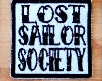 Op de afbeelding: Zwart-wit geborduurde patch met de tekst "LOST SAILOR SOCIETY" op een witte achtergrond.