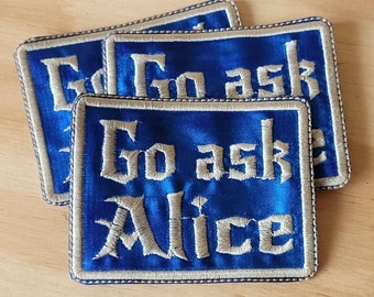 Peut inclure: Trois patchs en satin bleu avec des coutures blanches. Chaque patch dit "Go ask Alice" dans une police blanche stylisée.