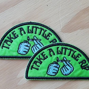 Könnte beinhalten: Zwei grüne und schwarze gestickte Patches mit dem Text "Take a little rip" und einem Cartoon-Bild von zwei Händen, die einen angezündeten Joint halten.