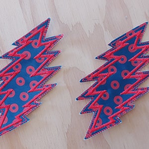 May include: Two blue and red lightning bolt shaped patches with a red and white polka dot pattern.