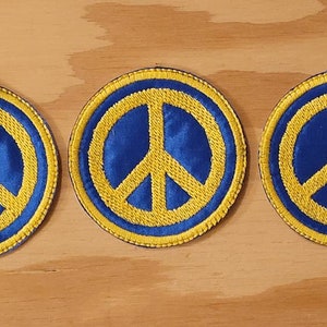 Peut inclure: Trois patchs ronds avec un signe de paix, fond bleu et signe de paix jaune.