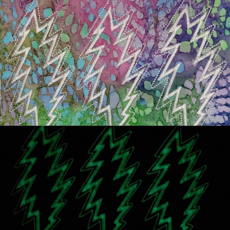 Puede incluir: Primer plano de un parche de tela con un patr&oacute;n tie-dye y un dise&ntilde;o de rayo blanco bordado. El parche est&aacute; sobre un fondo negro con un dise&ntilde;o de rayo verde que brilla en la oscuridad.